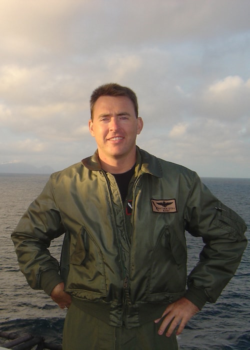 Fighter Pilot Matt Stoll standing on a ship with the ocean behind him